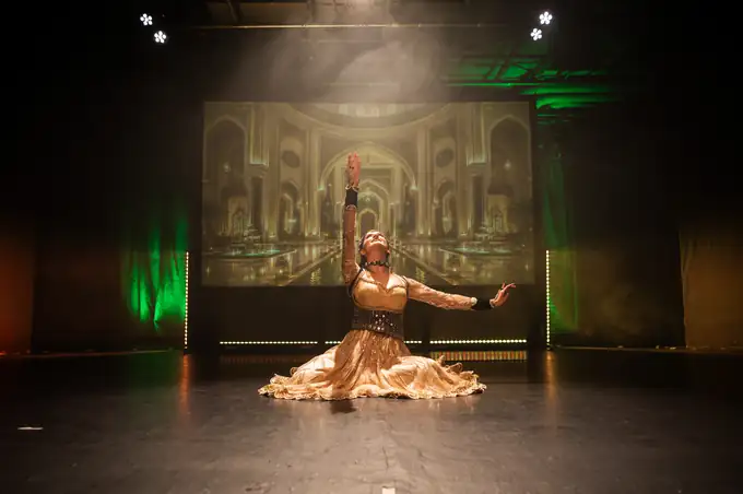 Soloist in a gold lehenga before a projected palace archway