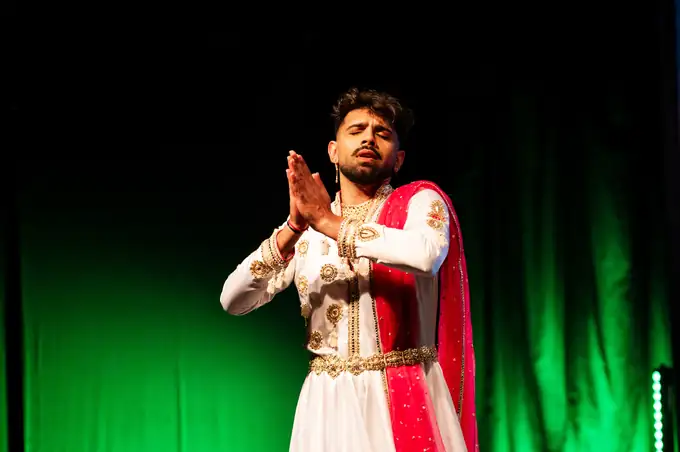 Soloist in white and gold with a red dupatta, hands joined
